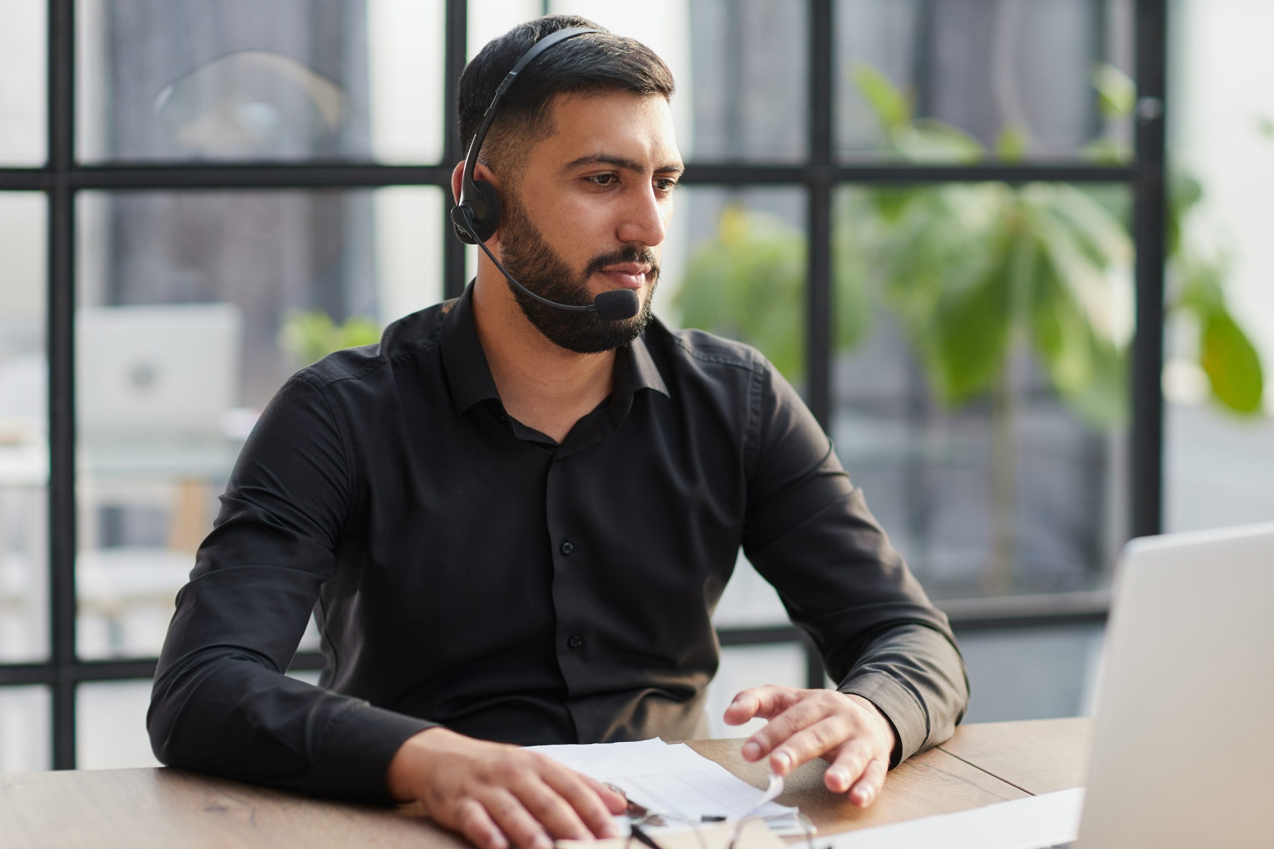 Young handsome male customer support phone operator with headset working in his office.